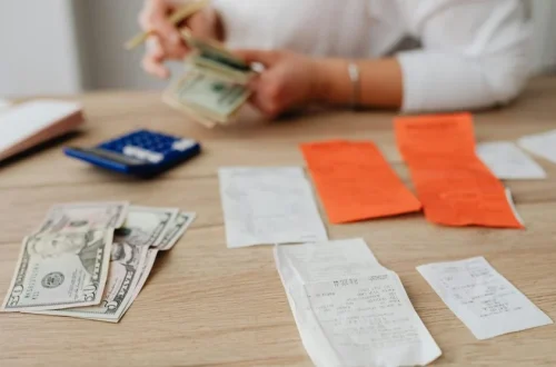 Person sitting at a desk with a laptop and papers, planning a budget